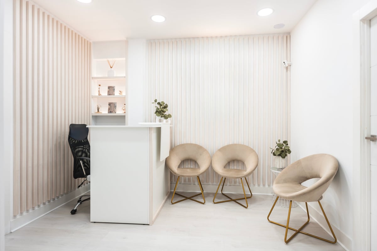Clean and bright modern clinic reception area showing a desk, stylish chairs, and decorative wall panels for wellness and healthcare