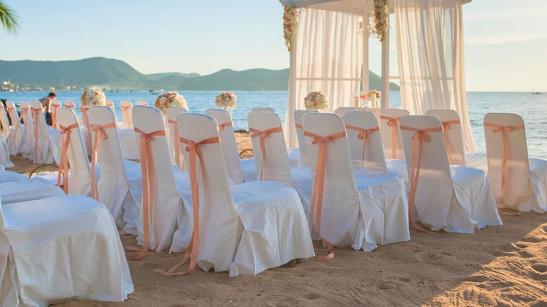 Elegant beach wedding ceremony setup with white chairs and ocean view
